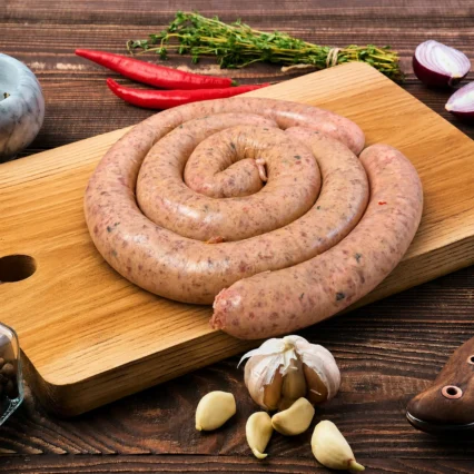 Chorizo en espiral sobre tabla de madera con ajo y cebolla morada