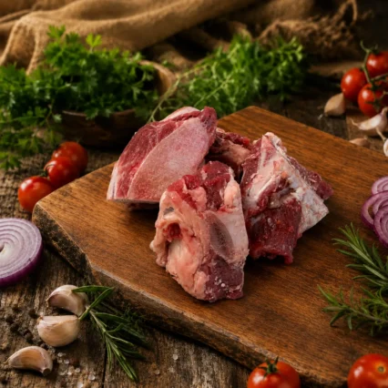 Huesos de res con carne para consomé sobre tabla de madera con vegetales