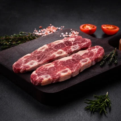 Tiras de asado con hueso sobre tabla de madera con tomate y tomillo