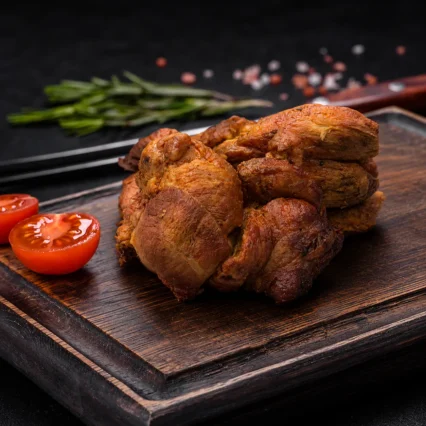 Chicharrón de carne dorado y crocante sobre tabla de madera con tomate