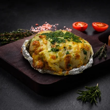 Papa asada con queso gratinado y hierbas envuelta en papel aluminio